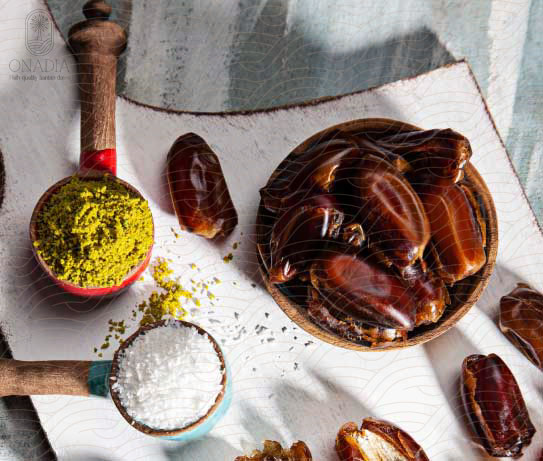 a bowl of sayer dates next to pistachio powder and coconut powder.